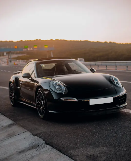 Black Porsche 911 with dark-tinted windows, front view — car window tinting in Dubai